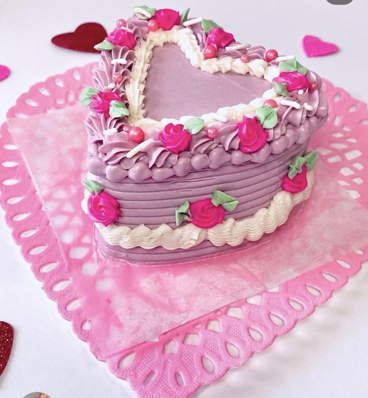 A small pink celebration cake with delicate piping